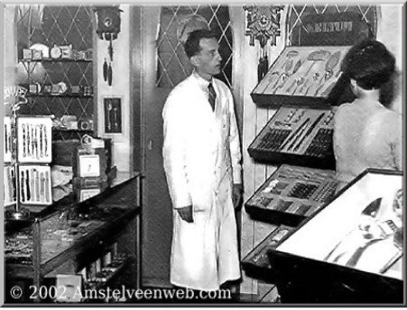 Historische foto van de juwelierszaak met een medewerker in witte jas